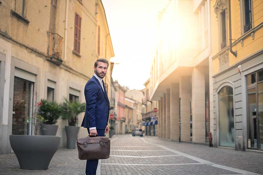 An English-to-Italian translator standing with suitcase in hand