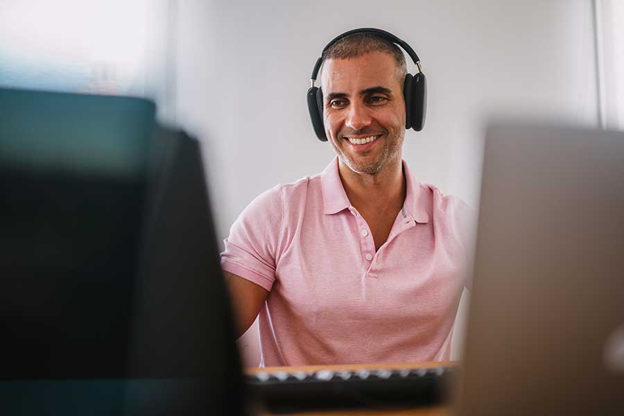 An English to Spanish translator smiling while working on his computer.