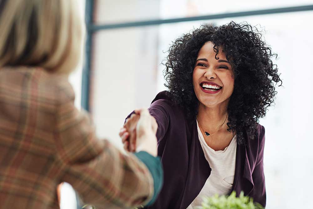 African American woman shaking hands with another woman. 